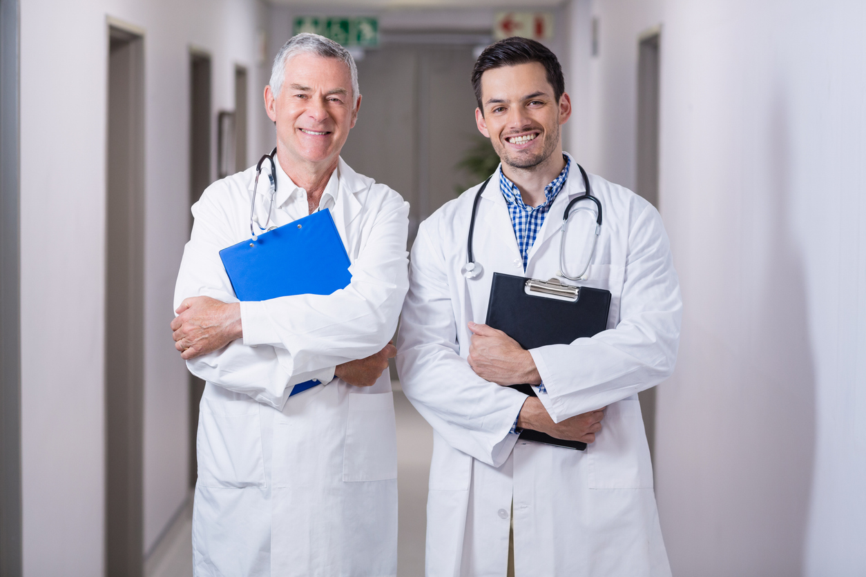 Portrait of smiling doctors standing together with clipboard in hospital corridor